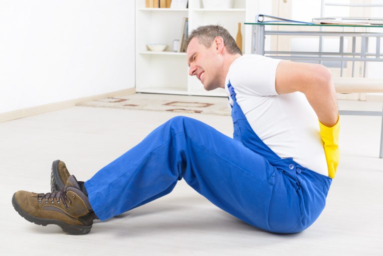 a man laying on the ground suffering from an injury in his workplace